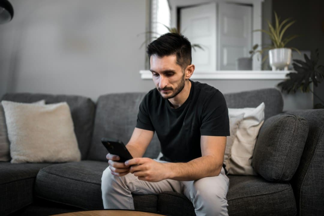 Man sitting on a grey couch using his smartphone